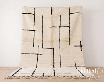 May include: A rectangular area rug featuring a cream-colored base with a geometric pattern of thin, black, intersecting lines. The rug has a soft, textured pile and a fringe along the bottom edge. The text Old Red City is visible in the bottom right.