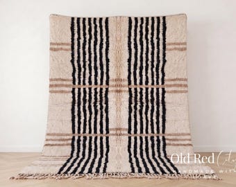 May include: A beige and black striped rug with a fringe at the bottom. The rug has vertical black stripes and horizontal brown stripes. The text "Old Red City" is visible in the bottom right corner.