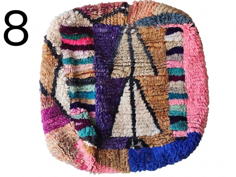 Puede incluir: Una colorida alfombra cuadrada de estilo marroqu&iacute; con un dise&ntilde;o de patchwork. La alfombra presenta una variedad de colores, incluyendo rosa, morado, azul y beige. El n&uacute;mero "8" est&aacute; en la esquina superior izquierda. La alfombra tiene una apariencia texturizada y tejida.