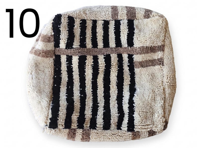 Puede incluir: Un puf cuadrado y texturizado con un fondo color crema y rayas negras verticales. El puf tambi&eacute;n presenta rayas marrones y el n&uacute;mero "10" en negro en la esquina superior izquierda. Este art&iacute;culo decorativo es adecuado para la decoraci&oacute;n del hogar.