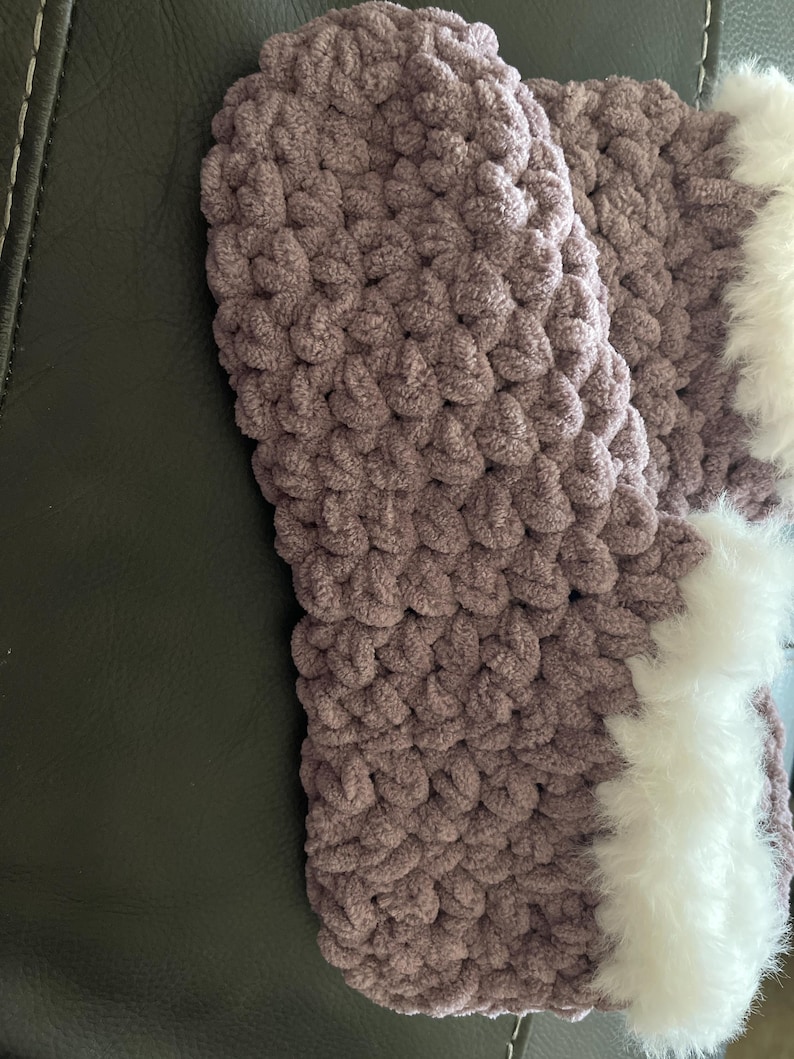 May include: Purple crocheted slippers with a white fluffy trim around the top edge.