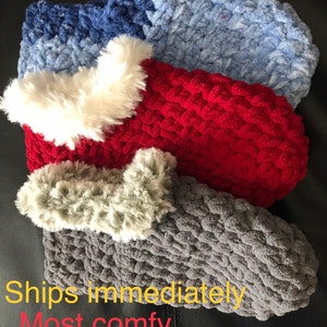 May include: Three pairs of cozy knitted slippers with faux fur trim. The slippers are in shades of gray, red, and blue.