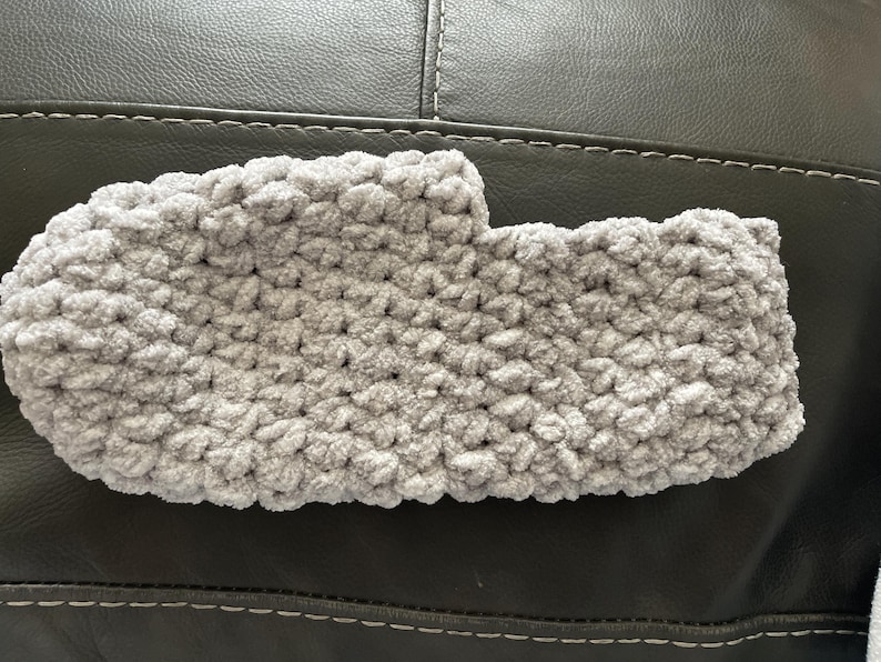 May include: A gray crocheted slipper with a fuzzy texture.