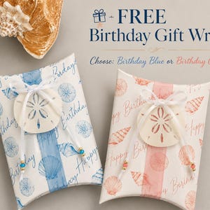 May include: Two rectangular pillow boxes with a seashell pattern and the text "Happy Birthday". One box features blue shells and text, the other coral shells and text. Each is tied with a white ribbon and a sand dollar ornament with small beads.