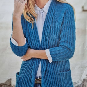 May include: A teal blue cardigan with long sleeves and two pockets. The cardigan is open in the front and has a ribbed texture.