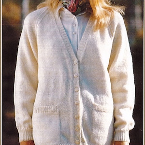 May include: A white knitted cardigan with a V-neck, long sleeves, and button closure. It has two patch pockets on the front and a ribbed hem and cuffs.