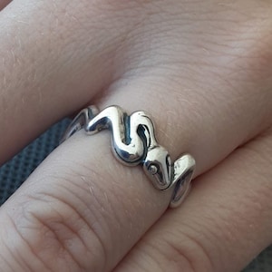 May include: A silver ring with a snake design. The snake is curled up and has a detailed head.