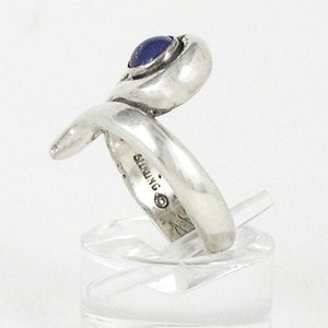 May include: Silver ring with a blue gemstone set in a twisted band. The ring is marked "STERLING" on the inside.