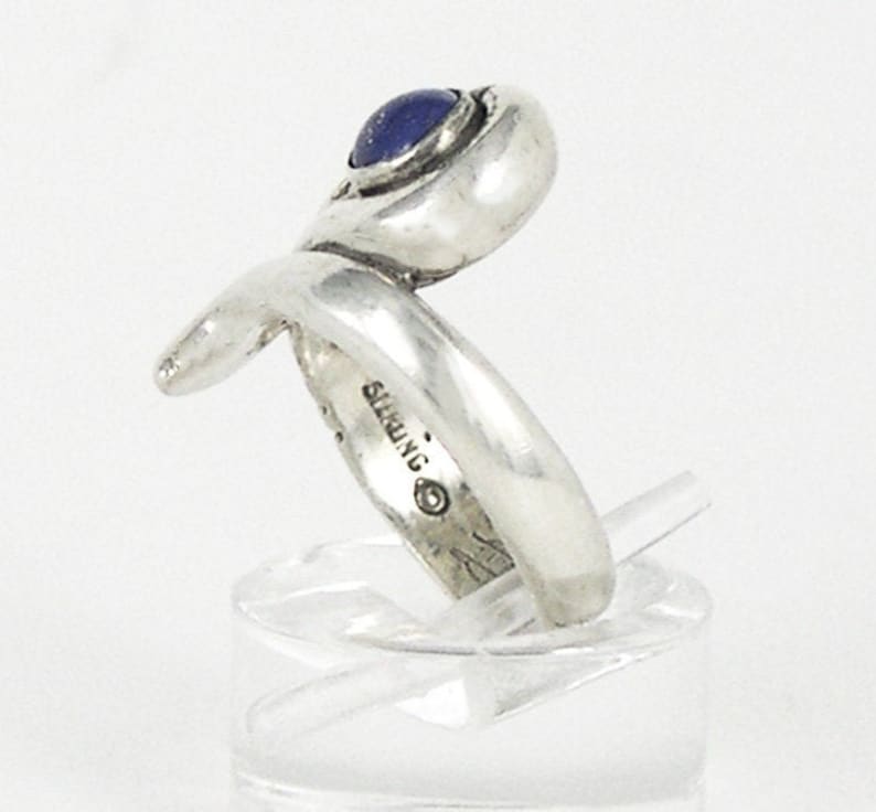 May include: Silver ring with a blue gemstone set in a twisted band. The ring is marked "STERLING" on the inside.