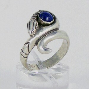 May include: A silver ring featuring a coiled snake design with a blue lapis lazuli gemstone.