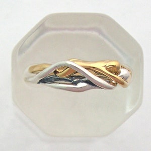 May include: A silver and gold intertwined ring with a unique design. The ring is displayed on a white octagonal background.