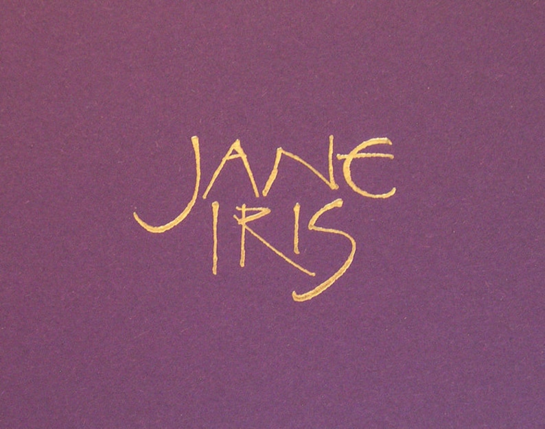 May include: A gold cursive signature that reads "Jane Iris" on a purple background.