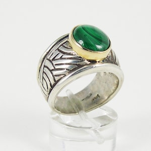 May include: A silver and gold ring with a green malachite stone. The ring has a textured band with a geometric design.