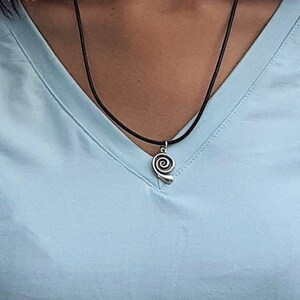 May include: A silver spiral pendant necklace on a black cord.