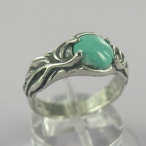 May include: A silver ring with a turquoise gemstone set in a delicate, branch-like design.
