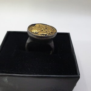 May include: A gold-plated ring with a black band and a design of a buffalo head on the top.