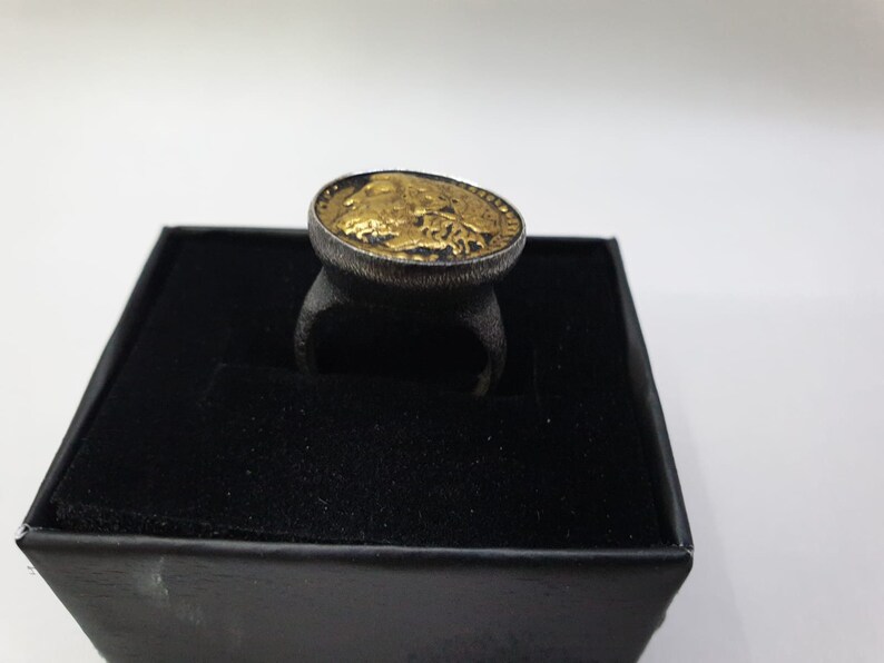 May include: A gold-plated ring with a black band and a design of a buffalo head on the top.