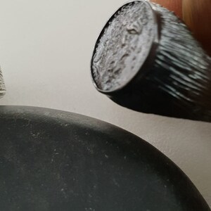 Puede incluir: Un anillo de sello de plata con una superficie texturizada. El anillo se lleva en un dedo.