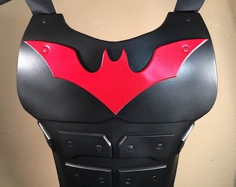 May include: Black and red plastic chest armor with a bat symbol. The chest armor has a textured surface and is designed to look like a superhero costume.