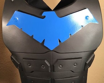 May include: Black and blue plastic chest armor with a blue bird logo. The armor has a textured surface and is designed to look like a superhero costume.