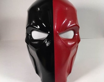 May include: A black and red half-face mask with a mesh eye covering. The mask is made of a smooth, hard plastic.