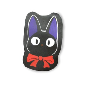 May include: A black cat with purple ears and a red bow tie. The cat has white eyes and a small pink nose.