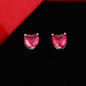 May include: A pair of heart-shaped earrings with pink gemstones set in silver.