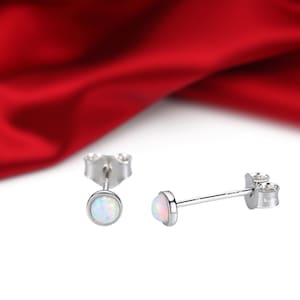 May include: A pair of silver stud earrings with small round white opal stones.