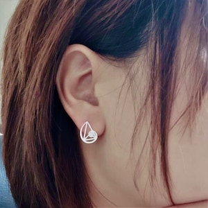 May include: A pair of silver geometric earrings with a spiral design. The earrings are small and delicate, and they would make a great gift for someone who loves minimalist jewellery.