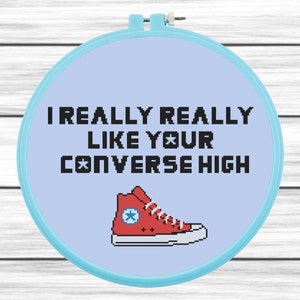 以下が含まれることがあります： 薄い青色の背景に黒い文字で「I really really like your converse high」と書かれた青い刺繍枠。テキストの下には白い星がついた赤いコンバースの靴が描かれている。