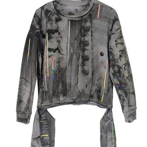 May include: A grey long-sleeved sweatshirt with an abstract design. The garment features vertical streaks of black and white, with colourful accents. The bottom of the shirt has two attached fabric panels. The shirt has a crew neck.