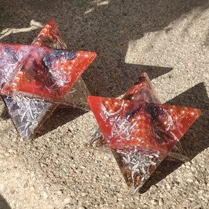 May include: Two red, black, and white star-shaped resin ornaments with a glittery finish.