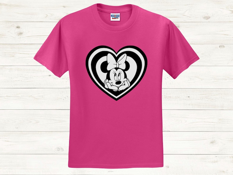 May include: A magenta t-shirt featuring a black and white Minnie Mouse graphic inside a heart shape. The graphic shows Minnie Mouse with her hands under her chin. The t-shirt is made of a soft material.