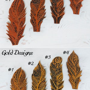 May include: Four copper and four gold feather-shaped bookmarks with black ink designs. The bookmarks are numbered 1 through 4 in both copper and gold.