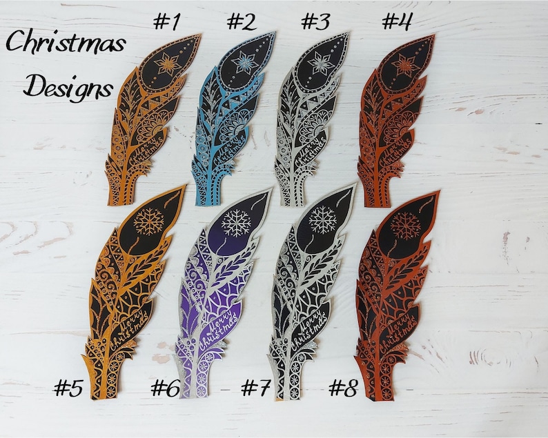 May include: A collection of eight decorative feather ornaments with intricate designs and the words "Merry Christmas." The feathers are in various colors, including gold, blue, silver, and orange. The text "Christmas Designs" is also visible.
