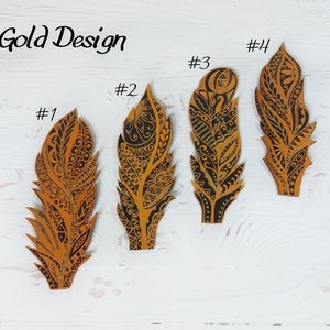 Puede incluir: Cuatro recortes decorativos de plumas con intrincados dise&ntilde;os en negro y dorado. Las plumas est&aacute;n numeradas y etiquetadas como "Gold Design". Cada pluma tiene un patr&oacute;n &uacute;nico, con elementos geom&eacute;tricos y florales.
