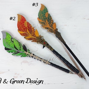 May include: Three decorative feather pens with black shafts and ornate metal tips. The feathers are painted in green, red, and gold with intricate designs. The pens are labeled #1, #2, and #3. The text "Red & Green Design" is at the bottom of the image.