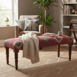 K&ouml;nnte beinhalten: Rote gepolsterte Bank mit geometrischem Muster in Blau, Gelb und Wei&szlig;. Die Bank hat dunkle Holzbeine und ist mit einem cremefarbenen Strickwurf bedeckt. Eine Tasse und B&uuml;cher liegen obenauf.