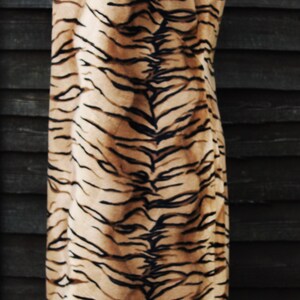 K&ouml;nnte beinhalten: Ein &auml;rmelloses Kleid mit einem Tigerstreifenmuster in Braun- und Schwarzt&ouml;nen.
