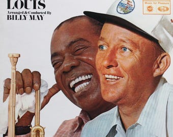 Pode incluir: Capa do álbum "BING & LOUIS" com Bing Crosby e Louis Armstrong. O texto inclui "Arranged & Conducted By BILLY MAY". Armstrong segura um trompete. Crosby usa um chapéu com um distintivo "Pebble Beach".
