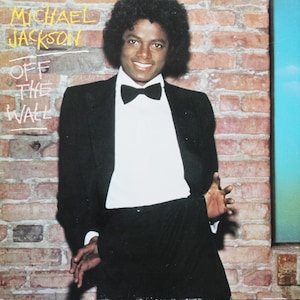May include: Album cover featuring Michael Jackson in a black tuxedo with a white shirt and bow tie, leaning against a brick wall. The album title "Off The Wall" is written in yellow and white text.