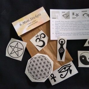 May include: A collection of six mini stickers featuring spiritual symbols, including a pentagram, Om symbol, and the Flower of Life. The stickers are black and white, with instructions on a white card. The stickers are on a brown paper background.