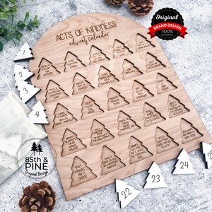 May include: A wooden Acts of Kindness advent calendar with a light wood finish. The calendar features 25 tree-shaped cutouts with daily acts of kindness. Includes numbered white wooden tree ornaments. The top reads "Acts of Kindness advent calendar."