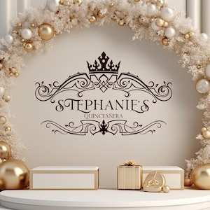 Op de afbeelding: Een decoratief decor voor een quinceañera-viering, met een crèmekleurige muur en een boog van witte en gouden ornamenten. De tekst "STEPHANIE'S QUINCEAÑERA" wordt weergegeven in elegant schrift. Gouden geschenkdozen en sokkels maken de feestelijke scène compleet.