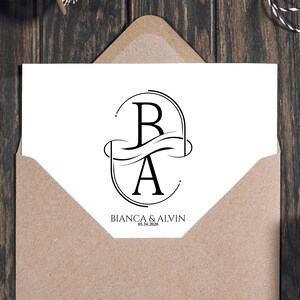 Puede incluir: Una tarjeta blanca con un dise&ntilde;o de monograma negro con las letras "B" y "A" dentro de un marco ovalado, con los nombres "BIANCA & ALVIN" y la fecha "05.14.2020" impresos debajo. La tarjeta est&aacute; dentro de un sobre marr&oacute;n, con otras cajas marrones en el fondo.