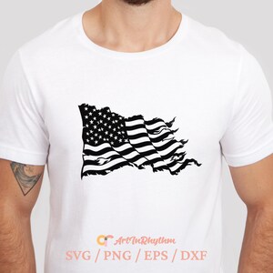 May include: A white t-shirt with a black and white distressed American flag design. The flag is waving in the wind. The text "Art in Rhythm" and "SVG/PNG/EPS/DXF" is printed on the bottom of the shirt.