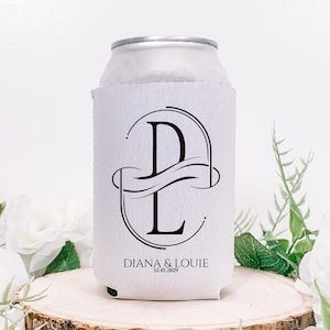 Puede incluir: Un enfriador de latas blanco con un dise&ntilde;o de monograma negro con las letras "D" y "L" entrelazadas. Los nombres "DIANA & LOUIE" y la fecha "12.01.2029" est&aacute;n impresos debajo. El enfriador est&aacute; sobre una superficie de madera.