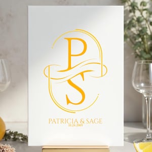 Puede incluir: Un letrero blanco con un monograma dorado de las letras "P" y "S" entrelazadas, con los nombres "Patricia & Sage" y la fecha "10.24.2009" debajo. El letrero se muestra sobre un soporte dorado.