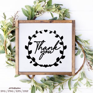 May include: A white sign with a black wreath of leaves and hearts surrounding the text "Thank you". The sign is framed in a brown wooden frame.