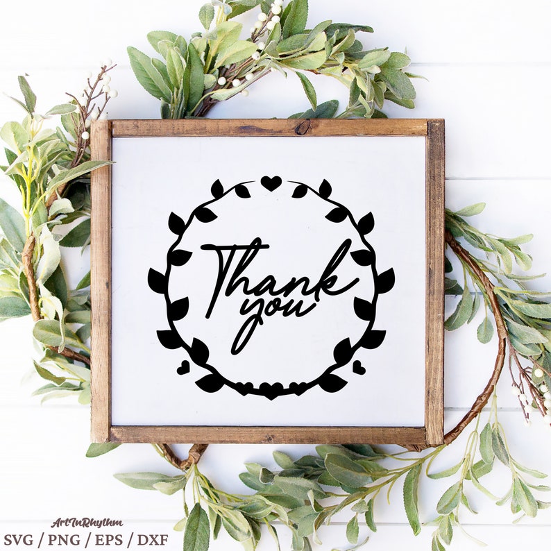 May include: A white sign with a black wreath of leaves and hearts surrounding the text "Thank you". The sign is framed in a brown wooden frame.